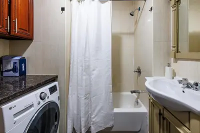 a bathroom with a washing machine and a sink at Discover the Comfort of Columbia University Area-4 in New York