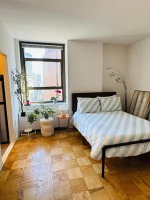 a bedroom with a bed and a wooden floor at Midtown Park Ave Charming Chrysler View Corner Studio in New York
