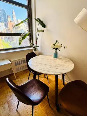 a table and chairs in a room with a window at Midtown Park Ave Charming Chrysler View Corner Studio in New York