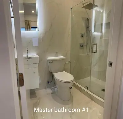 a white bathroom with a toilet and a shower at Modern 3BR,2BA Apartment in Jersey City, Easy Access to Manhattan in Jersey City