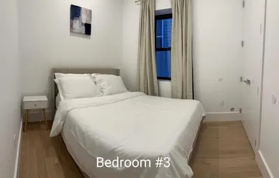 a bedroom with a bed with white sheets and a window at Modern 3BR,2BA Apartment in Jersey City, Easy Access to Manhattan in Jersey City