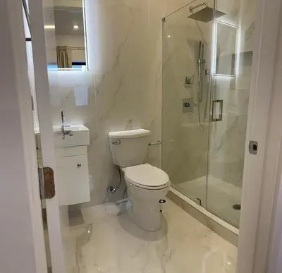 a white bathroom with a toilet and a shower at Modern 3BR,2BA Apartment in Jersey City, Easy Access to Manhattan in Jersey City