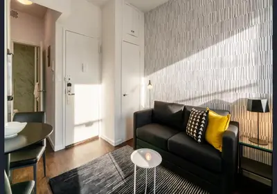 a living room with a black couch and a table at Modern Studio Apartment in NYC! in New York