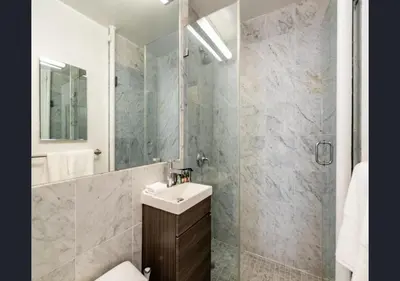 a bathroom with a sink and a shower with a mirror at Modern Studio Apartment in NYC! in New York