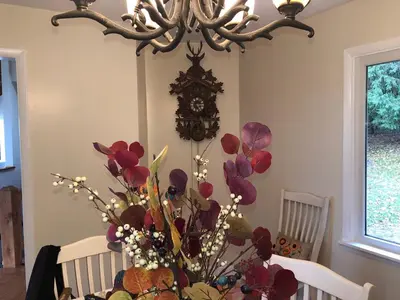 a dining room table with flowers and a clock on the wall at Mountain Retreat Stunning Views Hot Tub Fire Pit in Mehoopany