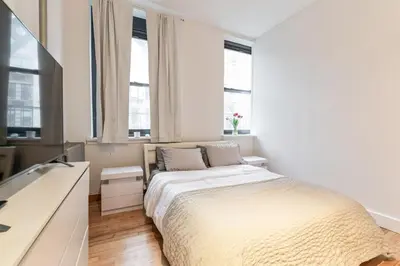 a white bedroom with a bed and two windows at XL Prime Tribeca Furnished Loft, June To Aug 90 Days Stay Required in New York
