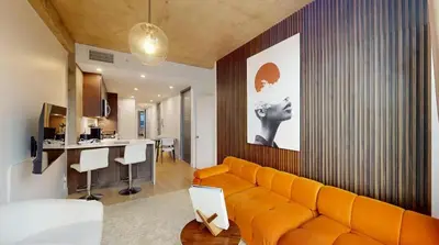 a living room with an orange couch and a kitchen at Sleek Two Bedroom in Manhattan in New York