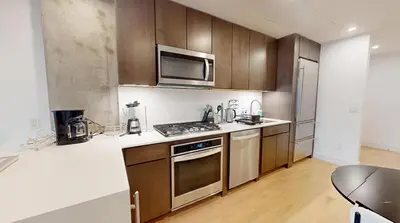 a kitchen with wooden cabinets and a stove top oven at Sleek Two Bedroom in Manhattan in New York