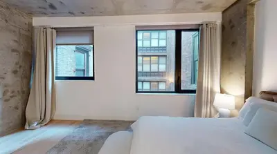 a bedroom with a white bed and two windows at Sleek Two Bedroom in Manhattan in New York