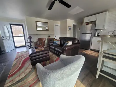 a living room with leather furniture and a kitchen at Riverfront Cottage in Owego in Owego