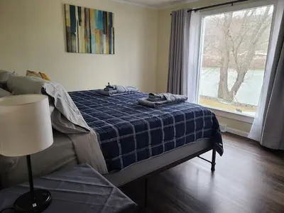 a bedroom with a bed with a blue blanket and a window at Riverfront Cottage in Owego in Owego