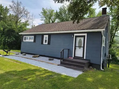a small blue house with a porch and stairs at Riverfront Cottage in Owego in Owego