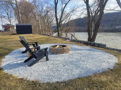 a park bench sitting next to a fire pit at Riverfront Cottage in Owego in Owego