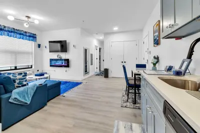 a living room with a blue couch and a kitchen at Blue Bliss Indoor Pool, FREE Parking, Near NYC in Elizabeth