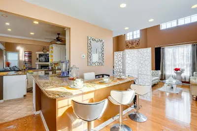 a kitchen and living room with a large island with white chairs at Theater and Game Room at Trenton Area Home in Edgewood Park