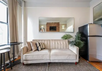 a white couch in a living room with a mirror at Upper West Side Furnished 1 Bedroom Apartment, June to Aug 90 days stay required in New York