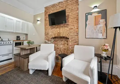 a living room with two chairs and a brick fireplace at Upper West Side Furnished 1 Bedroom Apartment, June to Aug 90 days stay required in New York