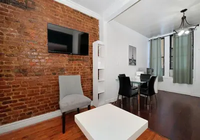 a living room with a brick wall and a table and chairs at Furnished 2 Bedroom Apartment Midtown West NYC, June To Aug 90 Days Stay Required in New York