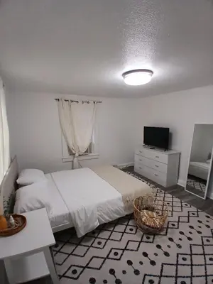 a bedroom with a bed and a television and a table at Monthly Stays - 2BR Apt in Bloomfield - 8 Min Walk from NJ Transit in Bloomfield