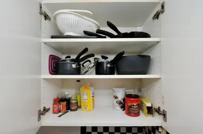 a kitchen cabinet filled with pots and pans at Furnished Apartment Room Rental In NYC, June To Aug 90 Days Stay Required in New York