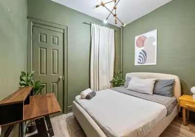 a bedroom with green walls and a bed and a table at Prime Murray Hill 2 BR Gem, June To Aug 90 Days Stay Required in New York
