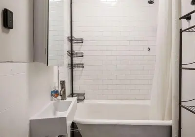 a white bathroom with a tub and a sink at Prime Murray Hill 2 BR Gem, June To Aug 90 Days Stay Required in New York