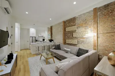 a living room with a couch and a brick wall at Spacious 2BR 2BA with Rooftop Walk to Times Square, June To Aug 90 Days Stay Required in New York