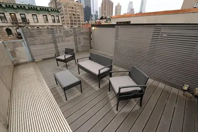 a balcony with chairs and benches on a building at Spacious 2BR 2BA with Rooftop Walk to Times Square, June To Aug 90 Days Stay Required in New York