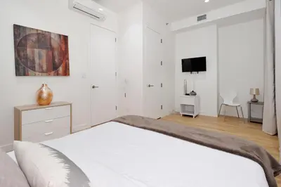 a white bedroom with a bed and a tv at Spacious 2BR 2BA with Rooftop Walk to Times Square, June To Aug 90 Days Stay Required in New York