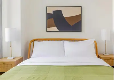 a bedroom with a bed with a green blanket and two lamps at Murray Hill 1 Bed Furnished Apt in New York