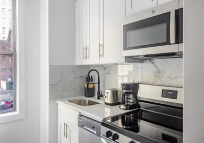 a kitchen with white cabinets and a stove top oven at Murray Hill 1 Bed Furnished Apt in New York