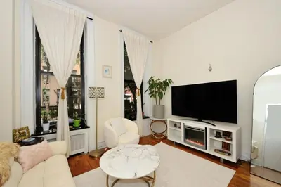 a white living room with a tv and a couch at Prime Location Murray Hill! Grand Central Station!, June To Aug 90 Days Stay Required in New York