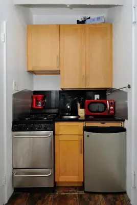 a kitchen with wooden cabinets and a red microwave at Prime Location Murray Hill! Grand Central Station!, June To Aug 90 Days Stay Required in New York