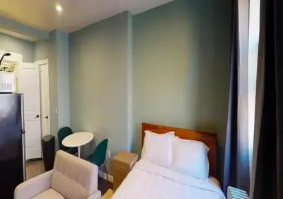 a bedroom with a bed and a chair and a table at Amazing Studio in Kips Bay! in New York