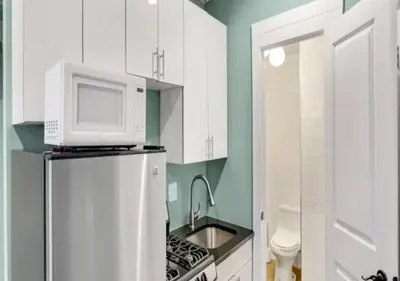 a white kitchen with a microwave on top of a refrigerator at Amazing Studio in Kips Bay! in New York