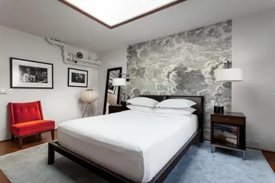 a bedroom with a large bed and a red chair at Roedonis SoHo in New York