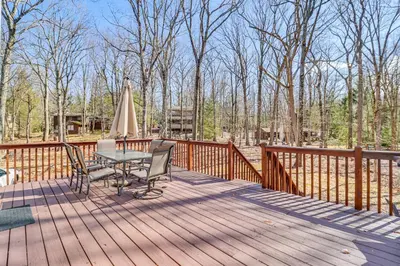 a wooden deck with a table and a umbrella at Walk to Lake Harmony Family Retreat with Decks! in Albrightsville