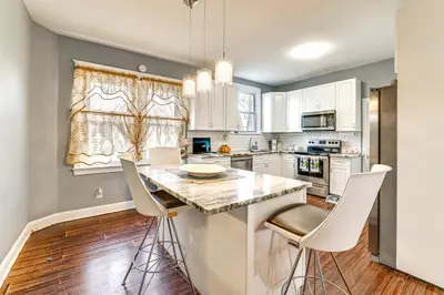 a kitchen with white cabinets and a island with bar stools at 3 Mi to Penn Pet-Friendly Townhome in Yeadon! in Yeadon