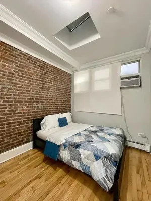 a bedroom with a bed and a brick wall at Great Location! Spacious 3BR Loft in Midtown West!, June To Aug 90 Days Stay Required in New York