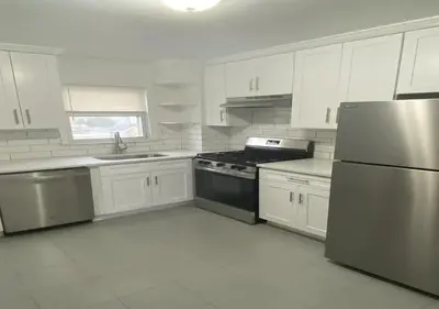 a kitchen with white cabinets and a stainless steel refrigerator at Great Location! Spacious 3BR Loft in Midtown West!, June To Aug 90 Days Stay Required in New York