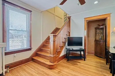 a living room with a staircase and a television at Suites On Chocolate - The Hershey House in Hershey