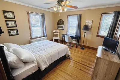 a bedroom with a bed with a ceiling fan and a desk at Suites On Chocolate - The Hershey House in Hershey