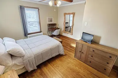 a bedroom with a bed and a television on a wooden dresser at Suites On Chocolate - The Hershey House in Hershey
