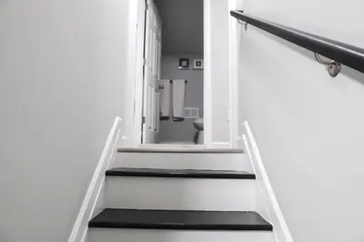 a hallway with stairs with a mirror and a bathroom at 8BR 4BA Home Near NYC -Sleeps 16 in Irvington