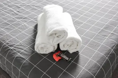 a towel laying on top of a bed with a remote control at 8BR 4BA Home Near NYC -Sleeps 16 in Irvington