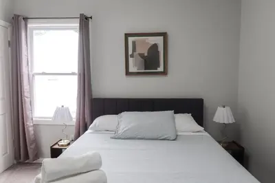 a bedroom with a bed with white sheets and a window at 8BR 4BA Home Near NYC -Sleeps 16 in Irvington