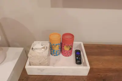 two cups and a remote control sitting on a white tray at Private Studio 5 minutes to the NYC train in Bayonne