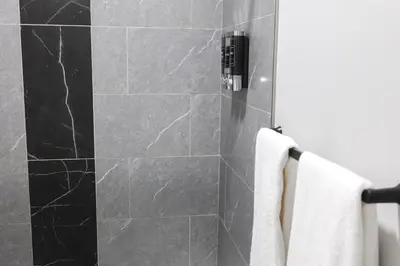 a bathroom with a shower with black marble tiles at 3Bed 2Bath Apt Near NYC plus Parking and Laundry in Irvington