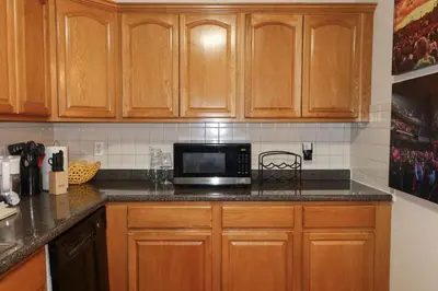 a kitchen with wooden cabinets and a microwave at 1Bed 1Bath Apt near EWR, Parking 18 min from Penn St. in Newark