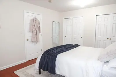 a white bedroom with a bed and a mirror at 1Bed 1Bath Apt near EWR, Parking 18 min from Penn St. in Newark
